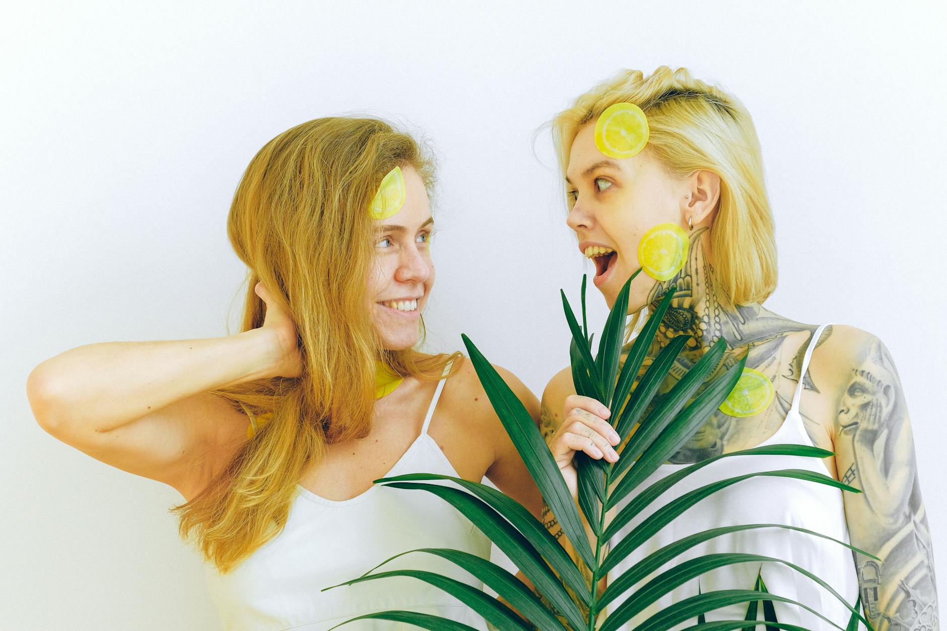 Two smiling women expressing joy and comfort with tropical plant, representing body acceptance and pleasure