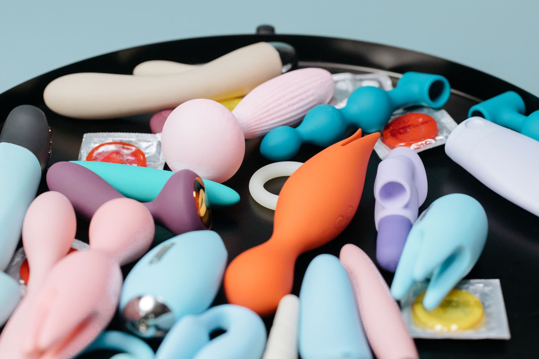 A vibrant collection of various sex toys on a black tray, featuring diverse shapes and colors