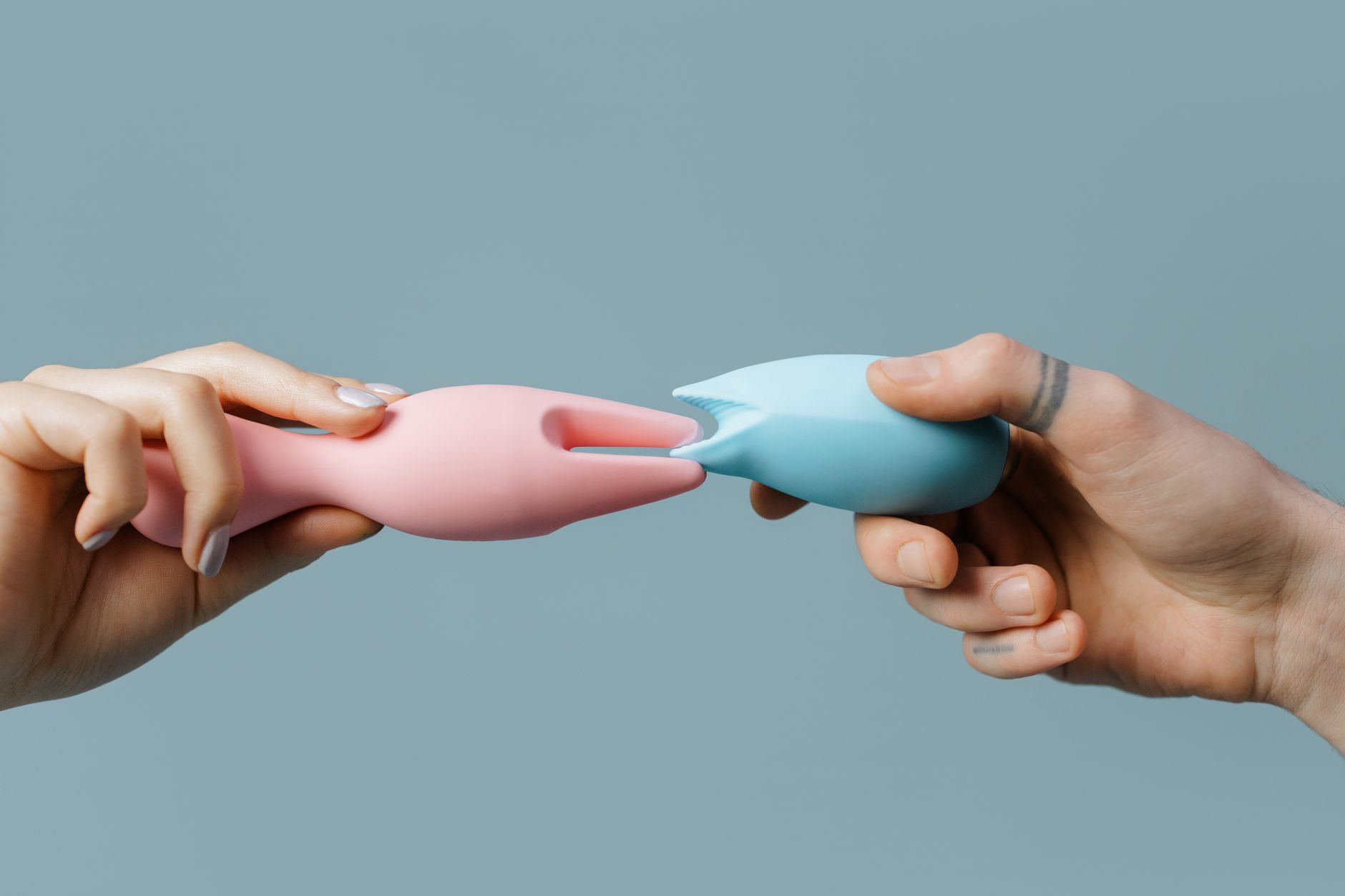 Woman holding a pink vibrator with art books in the background, illustrating intimate pleasure and personal wellness