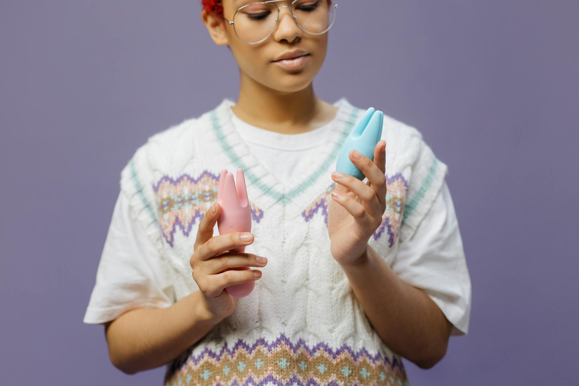 A person in a thoughtful moment holding colorful silicone vibrators, representing the intersection of pleasure and emotional healing.