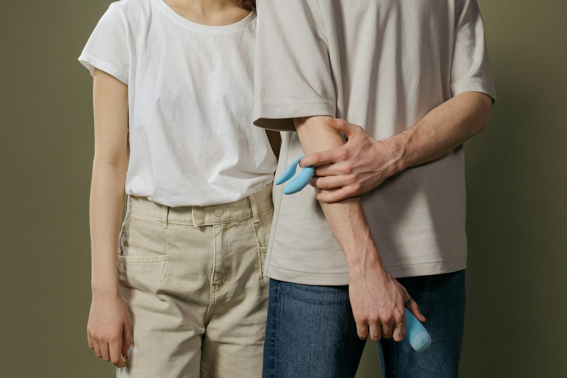 A couple holds a blue vibrator together, symbolizing modern intimacy and partnership during pleasure.